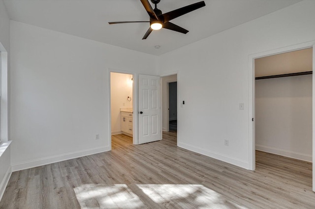 unfurnished bedroom with ensuite bath, ceiling fan, a spacious closet, light hardwood / wood-style floors, and a closet