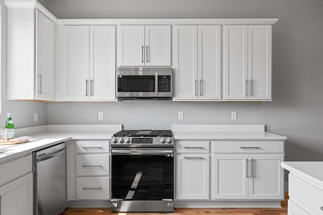 kitchen featuring light wood-type flooring, appliances with stainless steel finishes, and white cabinetry