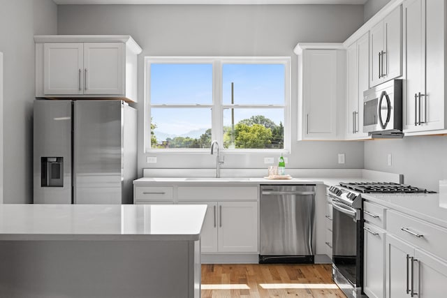 kitchen featuring light wood-type flooring, stainless steel appliances, white cabinetry, and sink