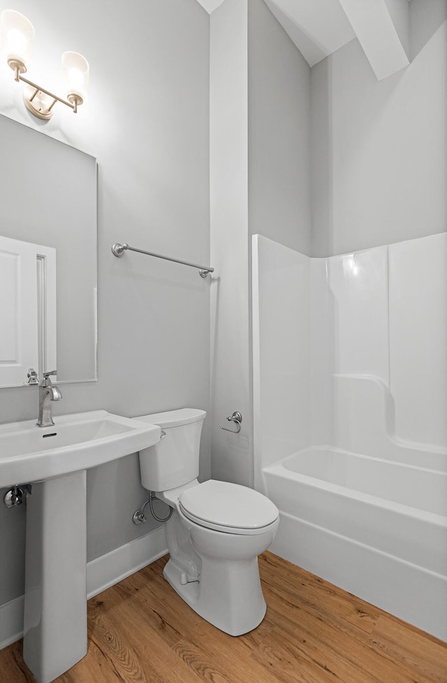 bathroom with shower / bathing tub combination, toilet, and hardwood / wood-style flooring