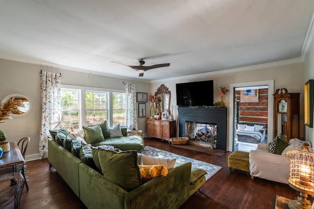 living room with dark wood-type flooring, ceiling fan, crown molding, and a brick fireplace