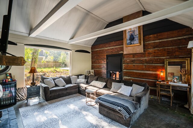 living room with lofted ceiling with beams, concrete flooring, and wooden walls