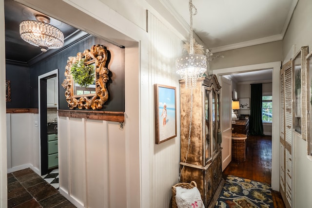 corridor with dark wood-type flooring, a notable chandelier, and ornamental molding