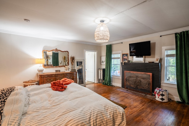 bedroom featuring dark wood-type flooring, ornamental molding, and a brick fireplace