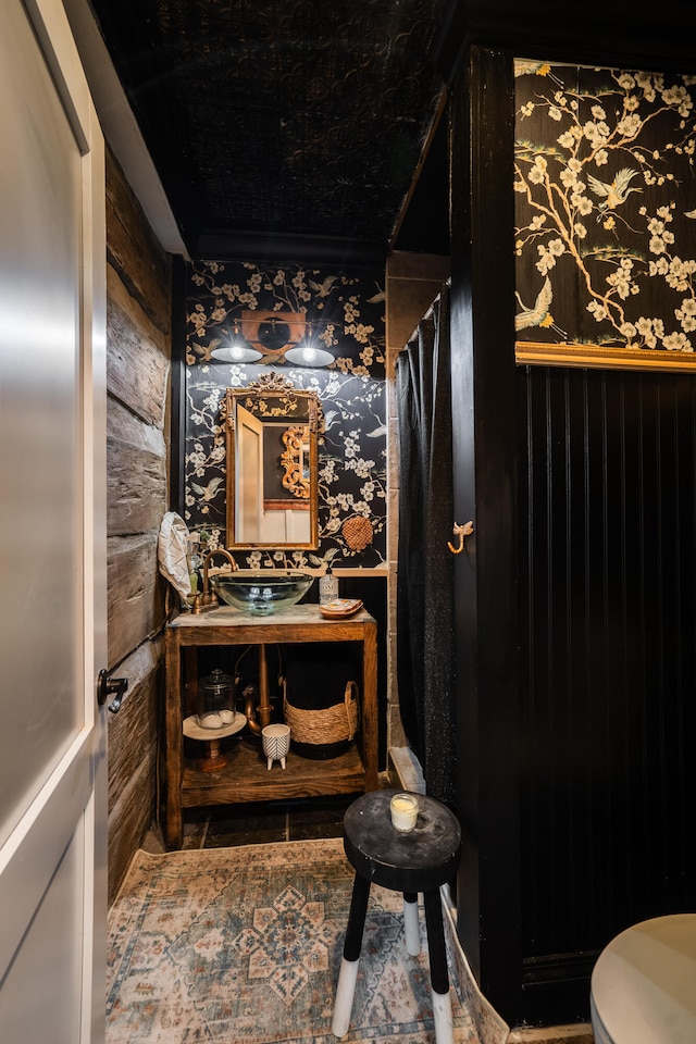 bathroom featuring a shower with curtain, toilet, wood walls, and sink