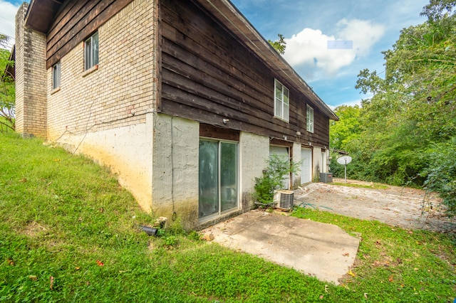 rear view of property with a lawn, a patio, and central AC unit