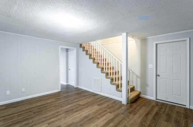 interior space with a textured ceiling, ornamental molding, and dark hardwood / wood-style flooring