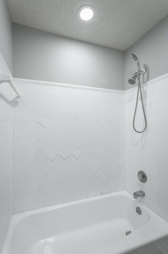 bathroom with tiled shower / bath and a textured ceiling