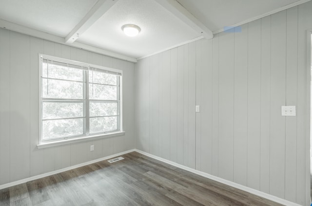 spare room with a textured ceiling, plenty of natural light, and dark hardwood / wood-style floors