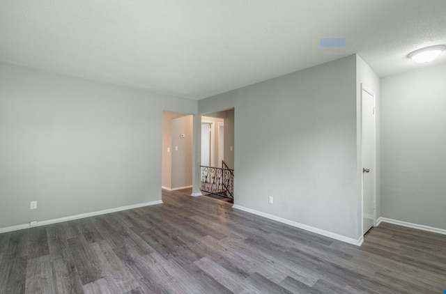 unfurnished room featuring dark wood-type flooring and a textured ceiling