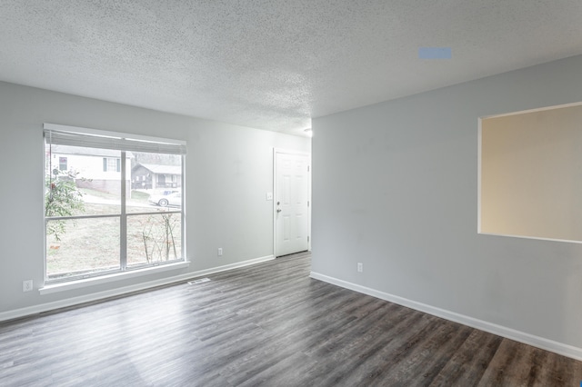 empty room with dark hardwood / wood-style floors and a textured ceiling