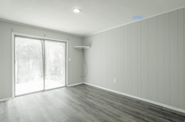 empty room featuring dark hardwood / wood-style floors, ornamental molding, and a textured ceiling