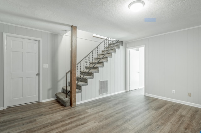 interior space featuring a textured ceiling, ornamental molding, and hardwood / wood-style flooring