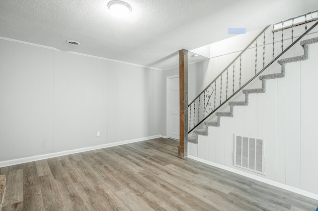 interior space with a textured ceiling, crown molding, and wood-type flooring