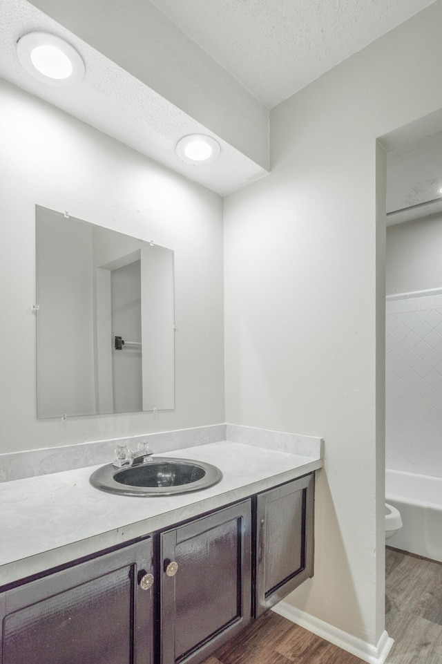 full bathroom featuring wood-type flooring, toilet, a textured ceiling, and vanity