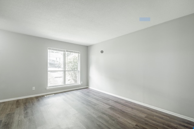 spare room featuring dark hardwood / wood-style flooring and a textured ceiling