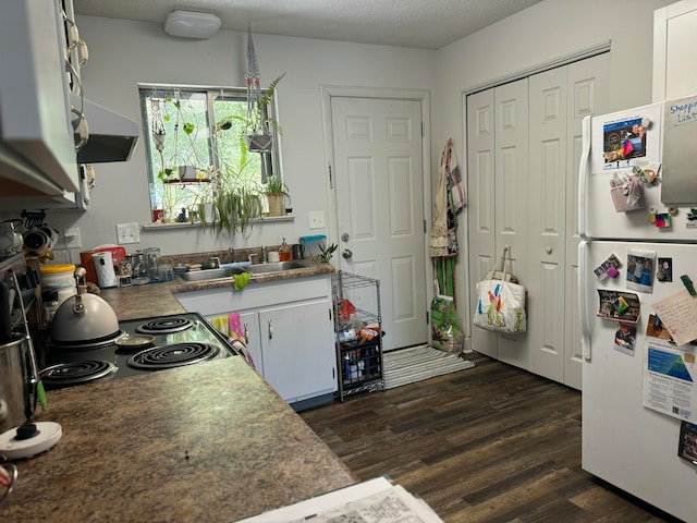 kitchen with white cabinets, a textured ceiling, sink, and white refrigerator