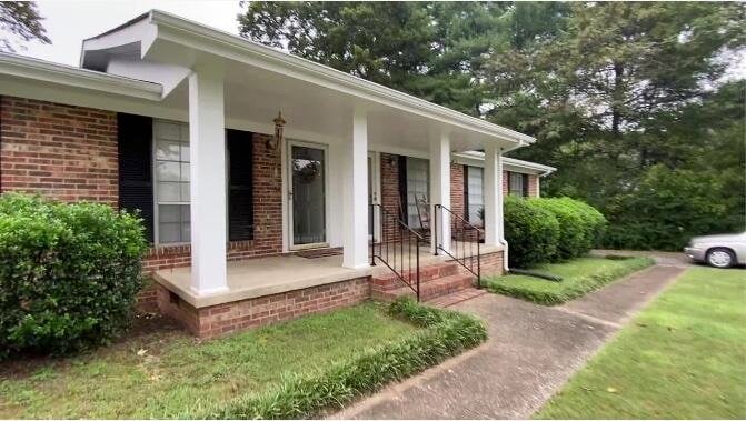 doorway to property with a porch and a lawn