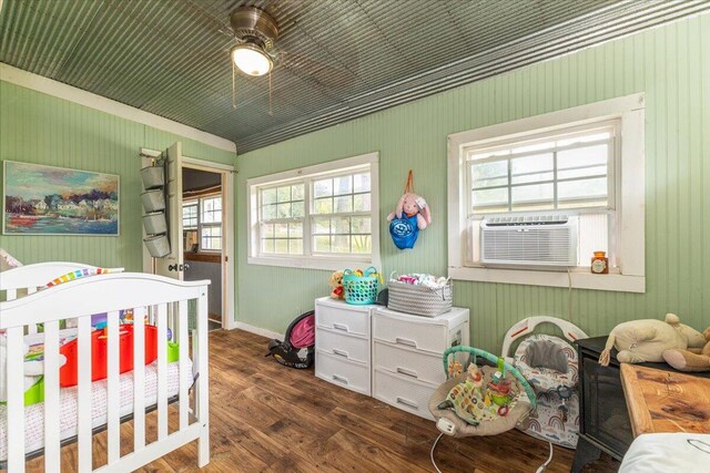 bedroom with a nursery area, cooling unit, ceiling fan, and dark hardwood / wood-style floors