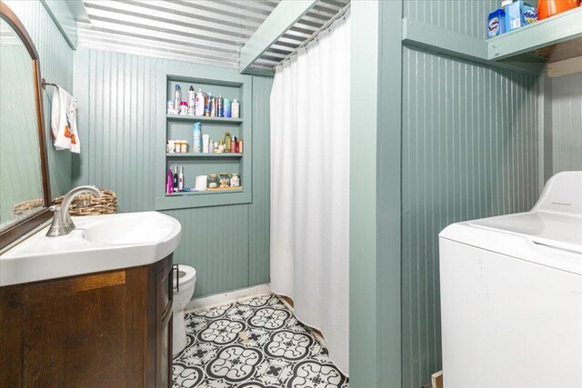 bathroom featuring vanity, toilet, wood walls, and washer / clothes dryer