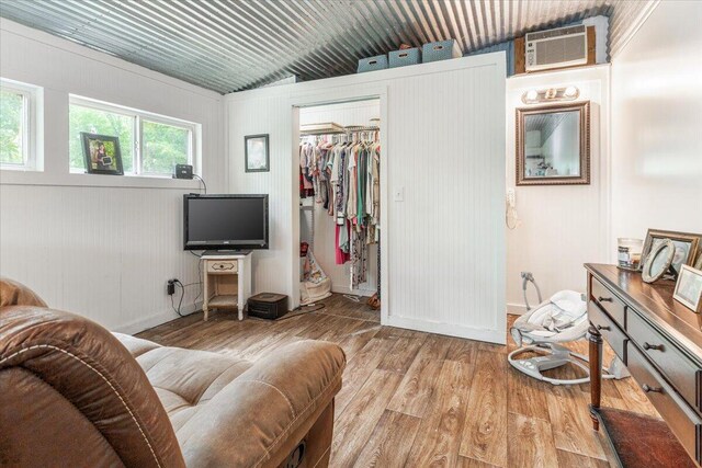 living room featuring lofted ceiling, a wall unit AC, and light wood-type flooring