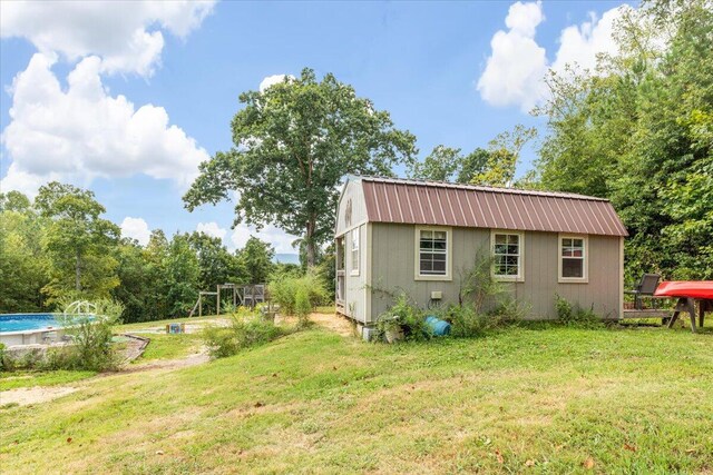 view of side of home featuring a yard and an outbuilding