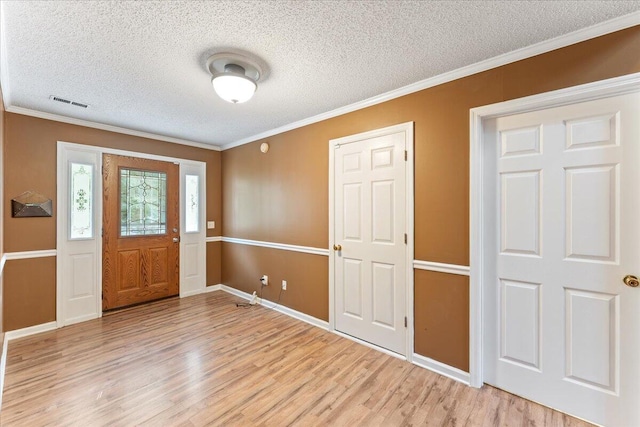 entryway with a textured ceiling, ornamental molding, and light hardwood / wood-style flooring