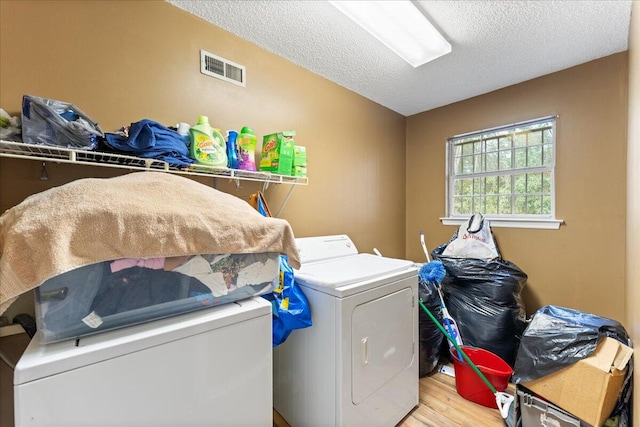 clothes washing area featuring a textured ceiling, washer and dryer, and hardwood / wood-style floors