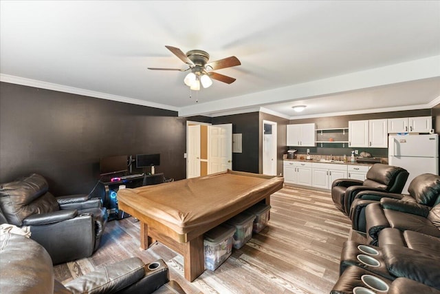 recreation room featuring ceiling fan, light wood-type flooring, crown molding, and sink