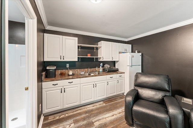 kitchen with white fridge, white cabinets, hardwood / wood-style floors, and sink