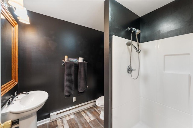 bathroom featuring a baseboard heating unit, sink, a shower, hardwood / wood-style floors, and toilet