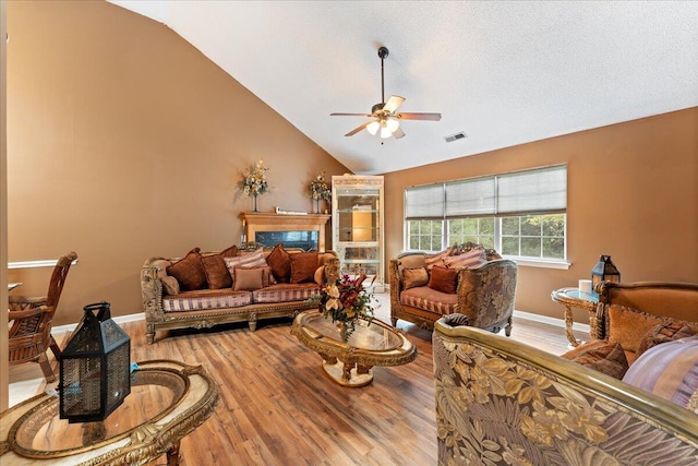 living room with lofted ceiling, a fireplace, hardwood / wood-style floors, and ceiling fan