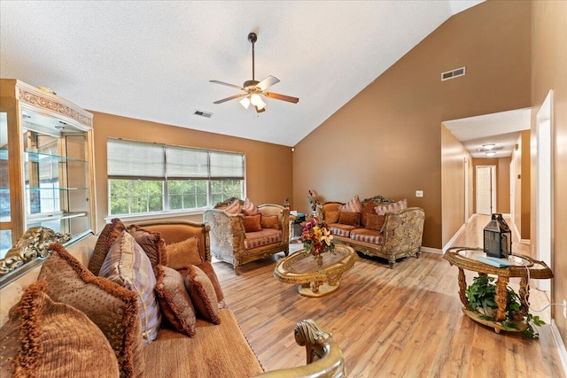 living room featuring ceiling fan, a textured ceiling, light hardwood / wood-style flooring, and high vaulted ceiling