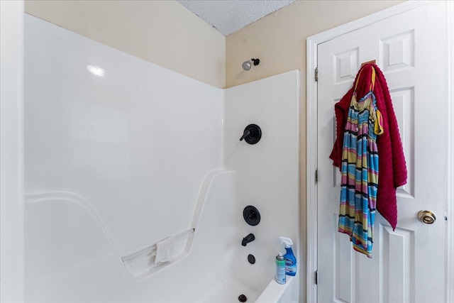 bathroom with a textured ceiling and tub / shower combination