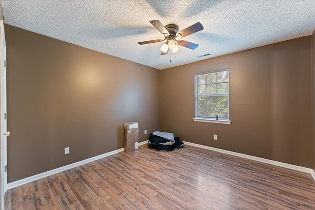 empty room with a textured ceiling, wood-type flooring, and ceiling fan