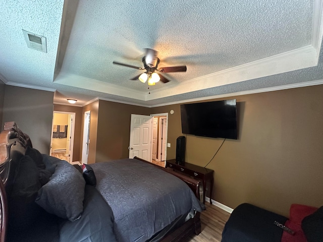 bedroom featuring ceiling fan, a textured ceiling, a tray ceiling, and ornamental molding