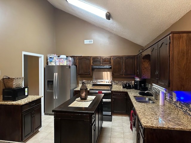 kitchen featuring stainless steel fridge, sink, a textured ceiling, high vaulted ceiling, and a center island