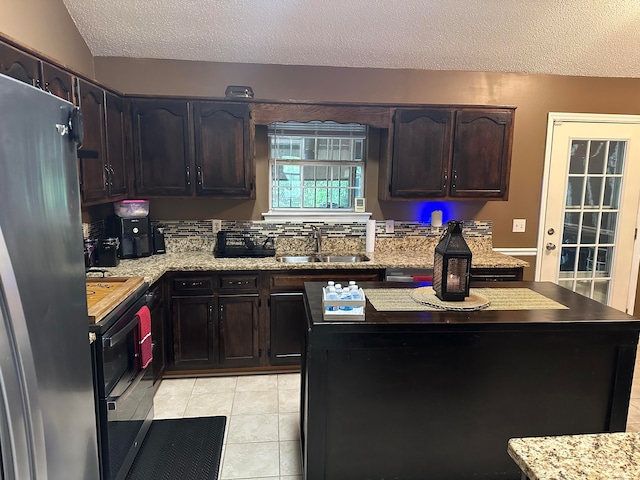 kitchen with dark brown cabinets, a textured ceiling, light tile patterned flooring, sink, and appliances with stainless steel finishes