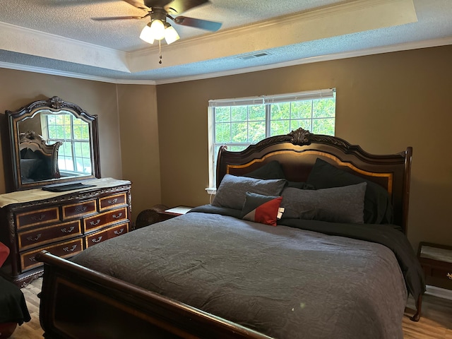 bedroom featuring a textured ceiling, ornamental molding, ceiling fan, and light hardwood / wood-style flooring