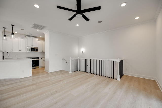 unfurnished living room featuring ceiling fan, ornamental molding, sink, and light hardwood / wood-style flooring