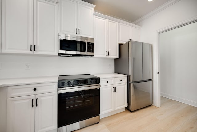 kitchen featuring crown molding, appliances with stainless steel finishes, white cabinets, and light hardwood / wood-style floors