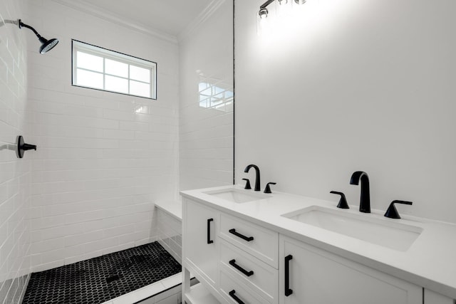 bathroom with crown molding, vanity, and a tile shower