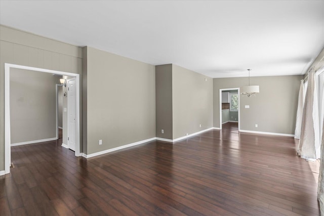 unfurnished room with an inviting chandelier and dark wood-type flooring