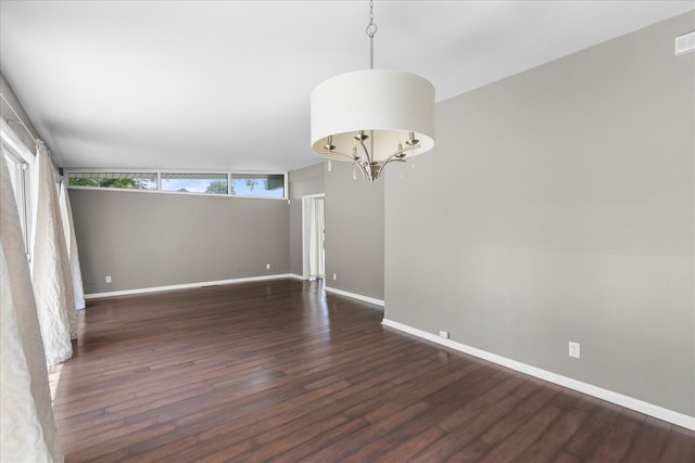 empty room with lofted ceiling, a chandelier, and dark wood-type flooring