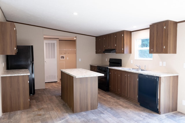 kitchen with crown molding, sink, black appliances, hardwood / wood-style floors, and a center island