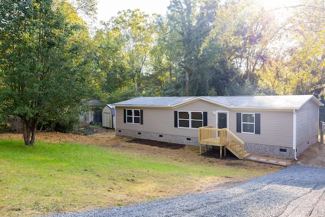 manufactured / mobile home with a front yard and a storage unit