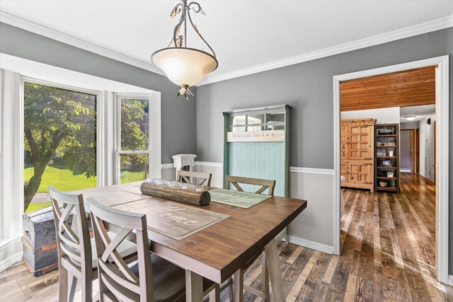 dining space with a textured ceiling, crown molding, and hardwood / wood-style flooring