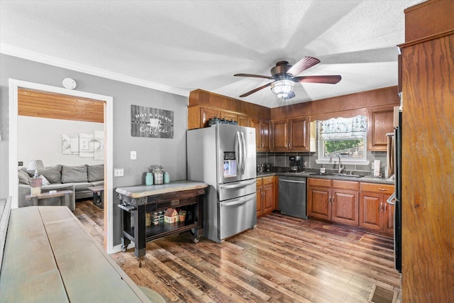 kitchen with hardwood / wood-style floors, backsplash, stainless steel appliances, sink, and ceiling fan