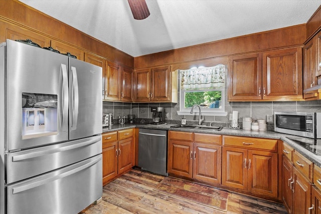 kitchen featuring backsplash, wood-type flooring, appliances with stainless steel finishes, sink, and lofted ceiling