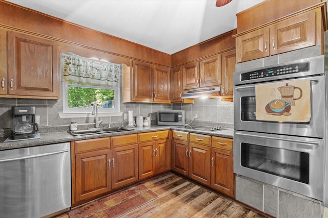 kitchen with hardwood / wood-style floors, appliances with stainless steel finishes, decorative backsplash, and sink